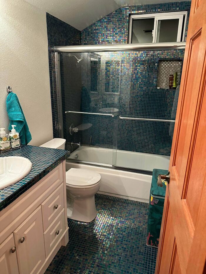 A bathroom with shimmering blue mosaic tiles covering the walls and floor, a stylish home decor project.