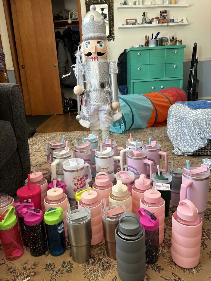 A large nutcracker surrounded by many colorful water bottles and tumblers, a unique and lucky find from dumpster diving.