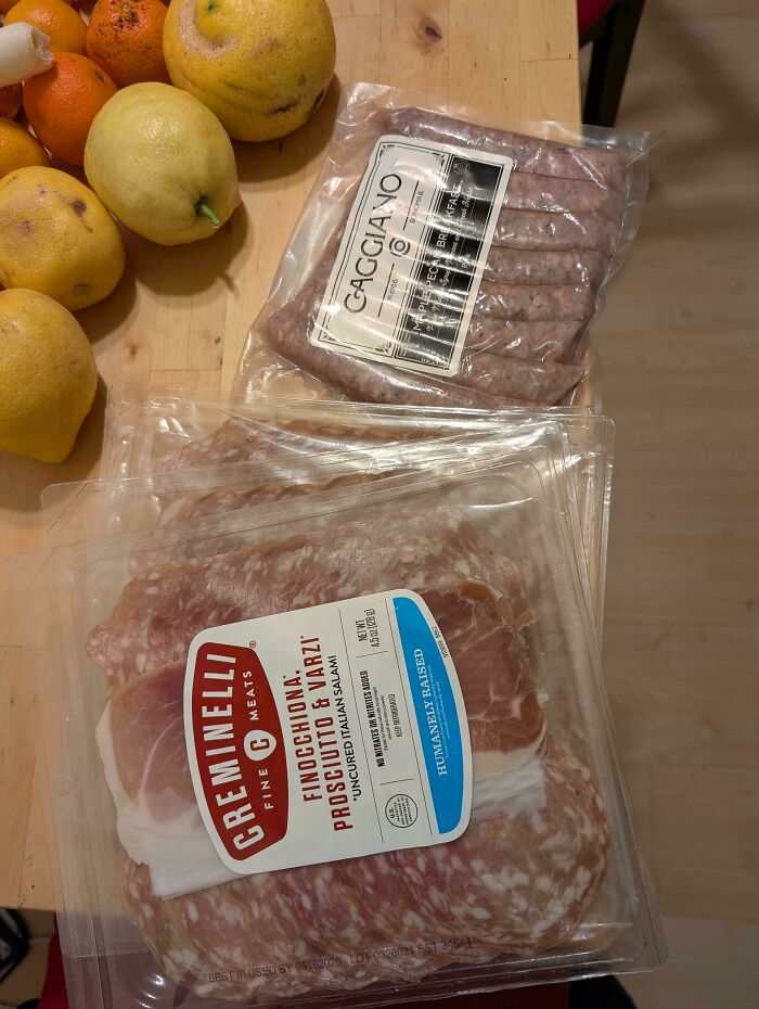 Packaged meats and fresh lemons on a wooden surface, highlighting a fortunate dumpster diving find.