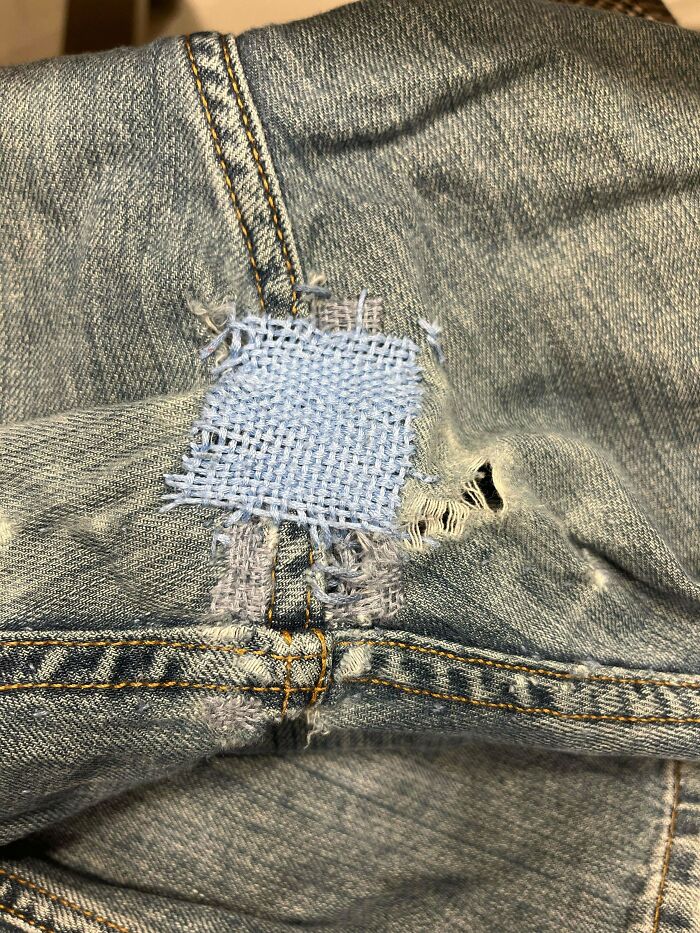 Close-up of denim jeans with a light blue patch sewn over a tear, showcasing Buy It For Life durability.