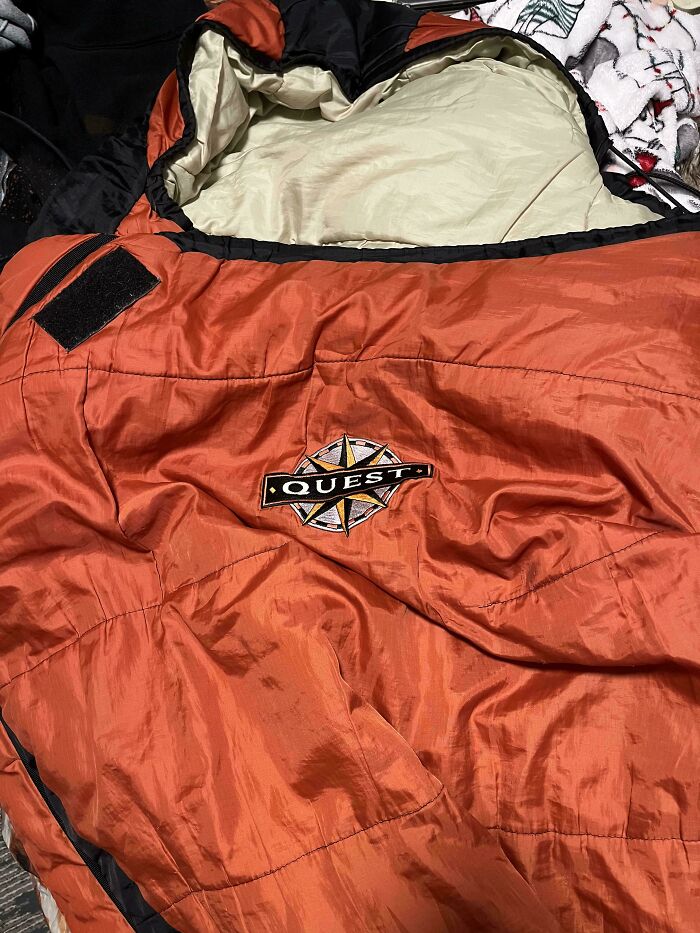 An orange sleeping bag with a black hood and the Quest logo, a Buy It For Life purchase for outdoor adventures.