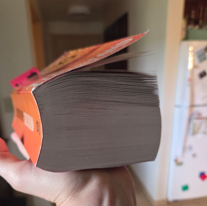 A thick book held in a hand, showing many pages from the side, a mildly interesting picture of its substantial size.