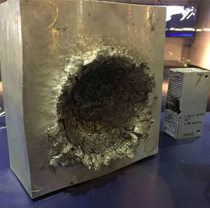 A large metal block with a massive impact crater, next to a smaller, damaged block, a picture made of online lies.