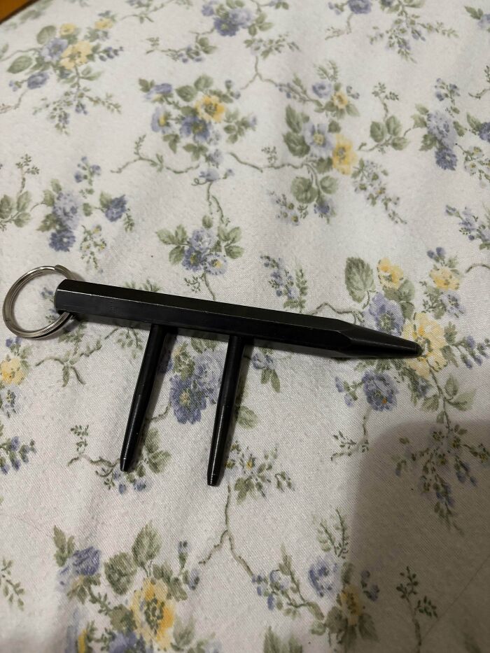 Black plastic object with three prongs and a keyring on floral fabric, a strange pic that leaves people utterly confused.