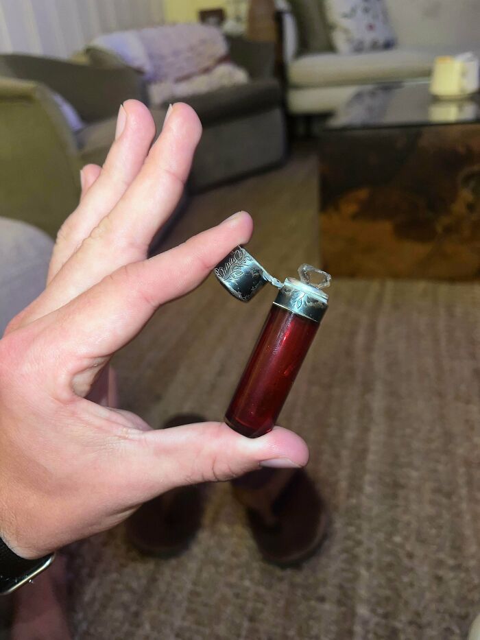 Hand holding a tiny vintage lighter with an intricate metal cap, a strange pic that shows unusual everyday objects.