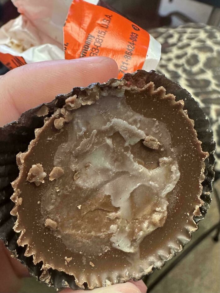 Partially melted peanut butter cup held in hand, showing an unusual texture in strange pics that confuse people.