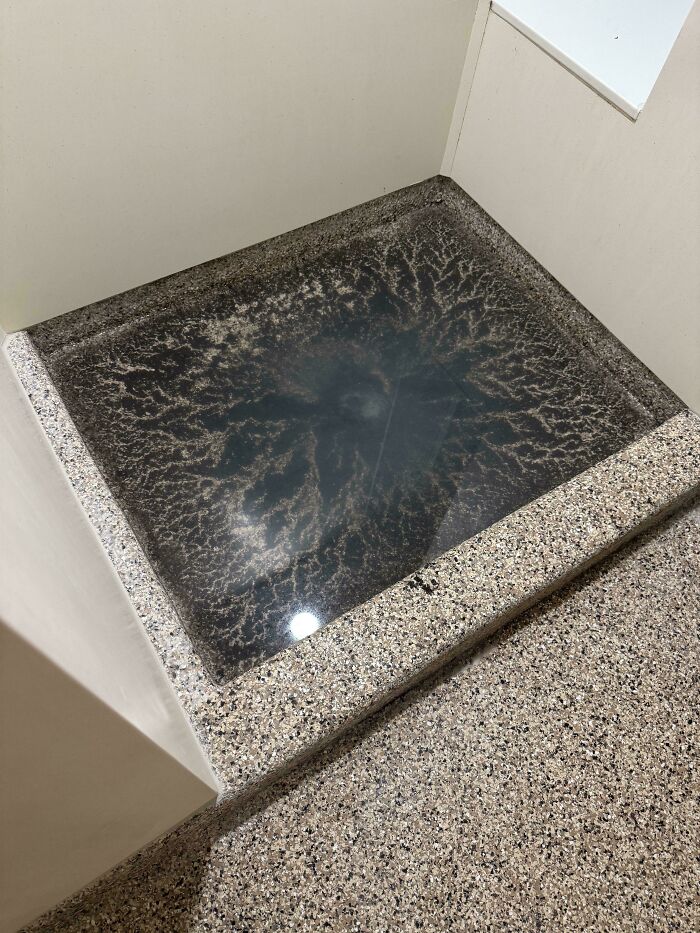 Strange pics showing a bizarre water stain inside a square basin creating an unusual and confusing pattern.