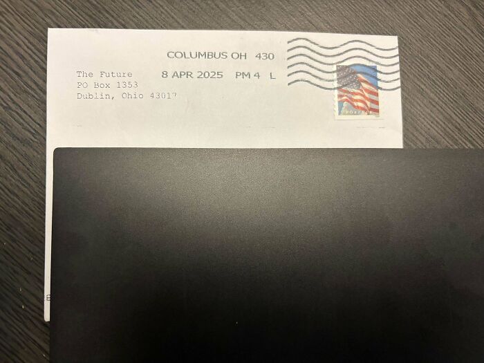 Envelope with a postmark from Columbus Ohio dated 2025 partly hidden under a black folder, a strange pic that causes confusion.
