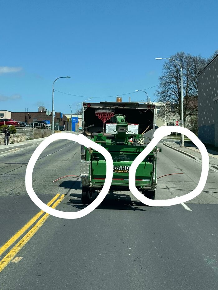 Green street cleaning vehicle on road with two sticks extending out, strange pics that cause utter confusion.