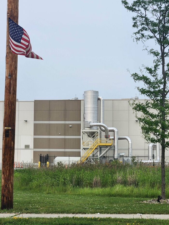 Industrial building with metallic pipes and an American flag, one of the strange pics that leave people utterly confused.