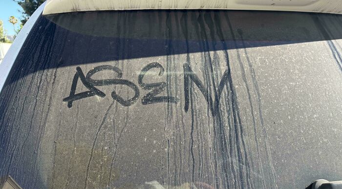 Dusty car window with a strange reversed graffiti drawing, capturing one of the strange pics people just had to take.