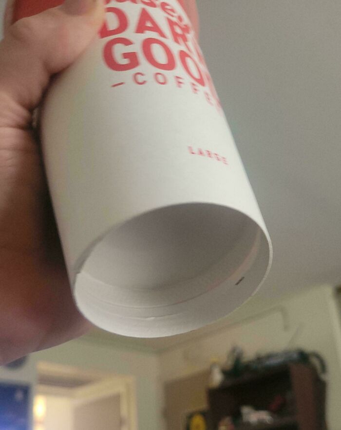 Hand holding coffee cup showing obvious shrinkflation with reduced inner cup size in America.