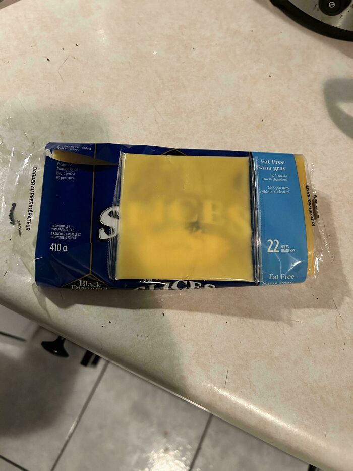 Shrinkflation example showing cheese package with fewer visible slices than advertised on kitchen counter surface.