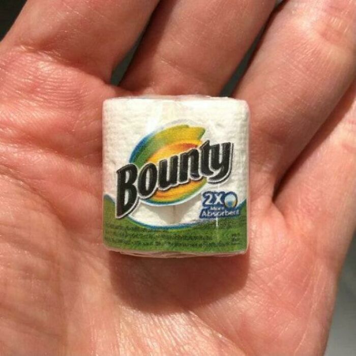 Miniature Bounty paper towel roll held in a hand, showcasing clear shrinkflation with a drastically reduced product size.