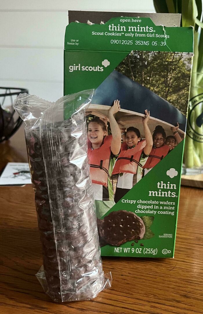 Girl Scouts Thin Mints box with partially empty cookie package showing obvious shrinkflation on wooden table.