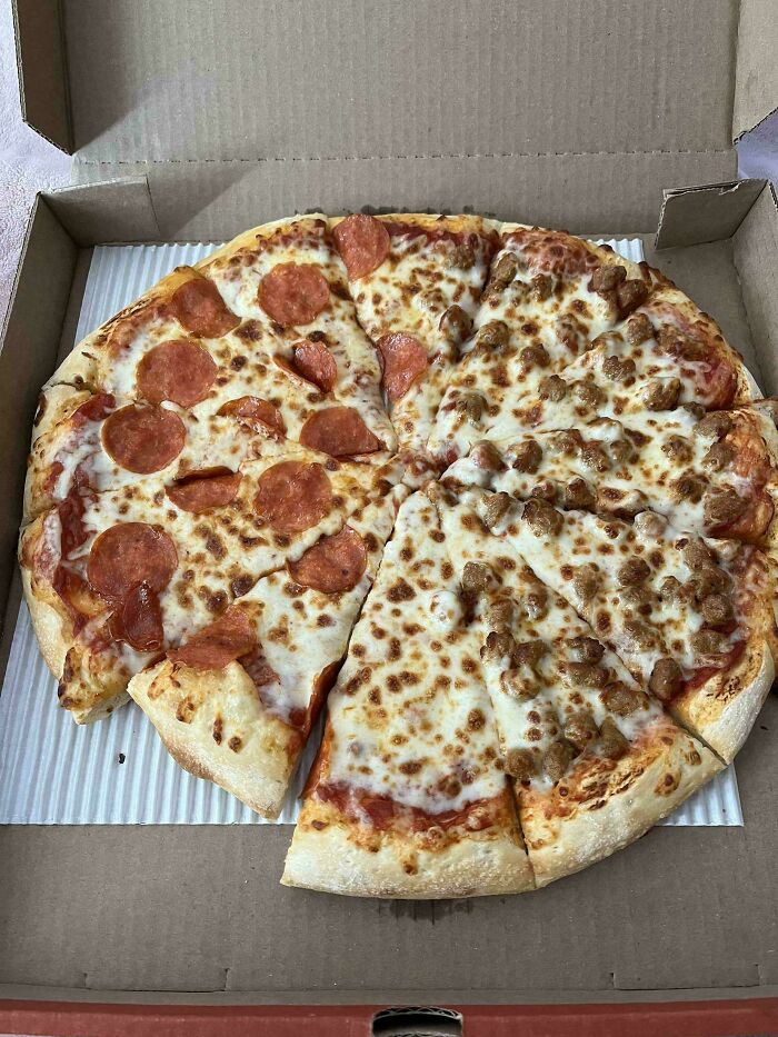 Pepperoni and sausage pizza with uneven slices illustrating shrinkflation in America, highlighting obvious size reduction.
