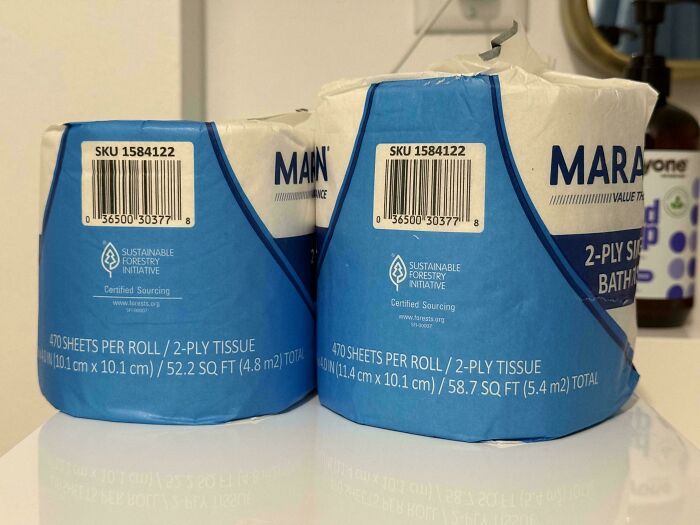 Two rolls of 2-ply tissue with shrinkflation showing different sheet counts and sizes on bathroom counter.