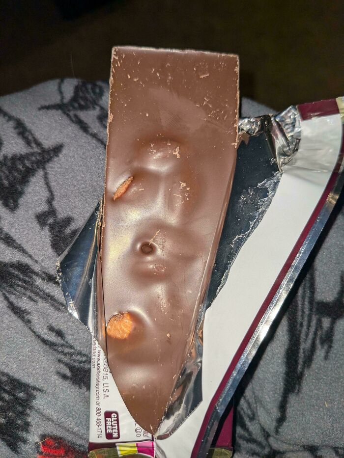 Half-eaten chocolate bar with uneven thickness and visible nuts, illustrating obvious shrinkflation in America products.