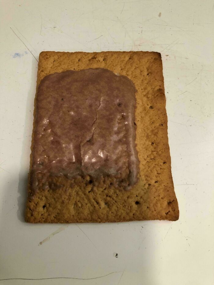 Partially covered graham cracker with noticeably reduced chocolate frosting illustrating obvious shrinkflation.