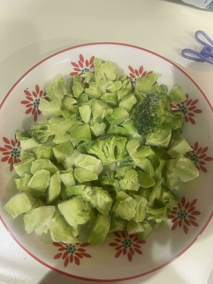 Frozen broccoli pieces in a floral bowl, illustrating shrinkflation with visibly smaller vegetable portion sizes.