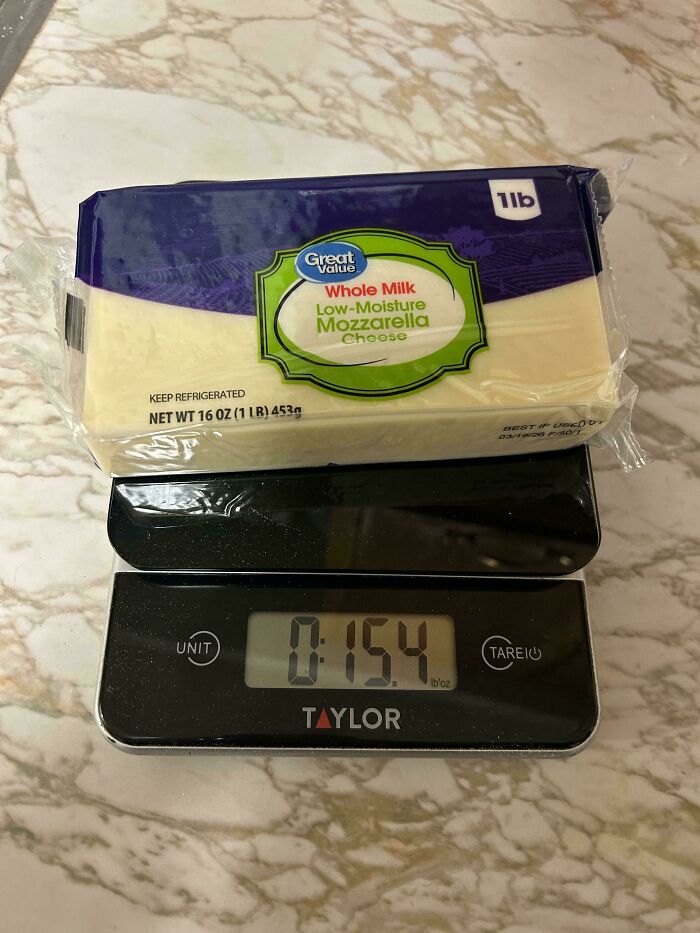 Package of Great Value mozzarella cheese weighed on digital scale showing 15.4 ounces illustrating shrinkflation in America.