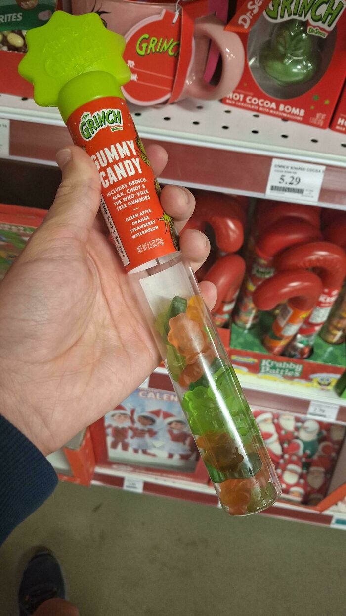 Hand holding Grinch gummy candy tube with fewer gummies visible, illustrating obvious shrinkflation in product packaging.