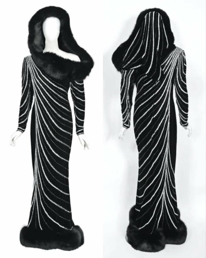 Black historical garment with fur trim and white swirling stripes, shown from front and back on mannequins.