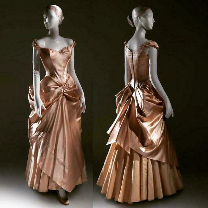 Elegant historical garments in shiny bronze fabric displayed on mannequins showcasing vintage dress design details