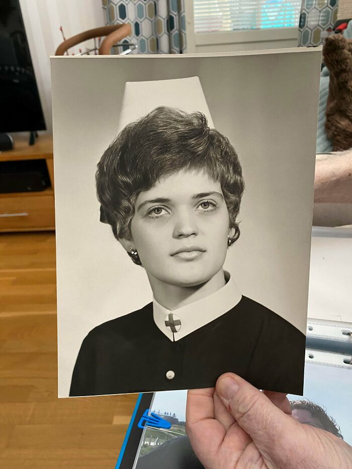 Black and white portrait photo from decades ago of a young woman with short hair, held by a person indoors.