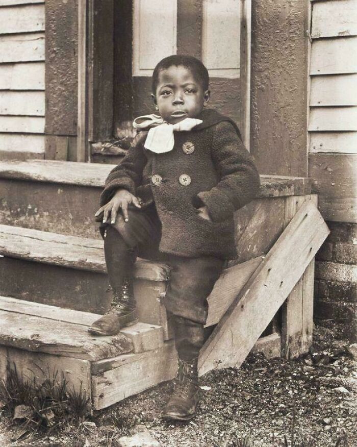 Vintage photo of a child sitting on wooden steps, illustrating powerful moments from decades ago captured in historic photos.