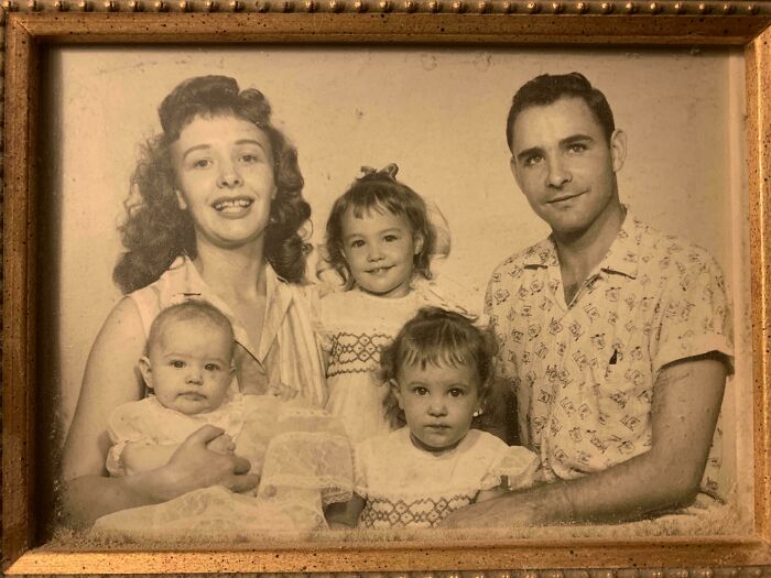 Vintage sepia family portrait from decades ago showing parents and three young children smiling together.