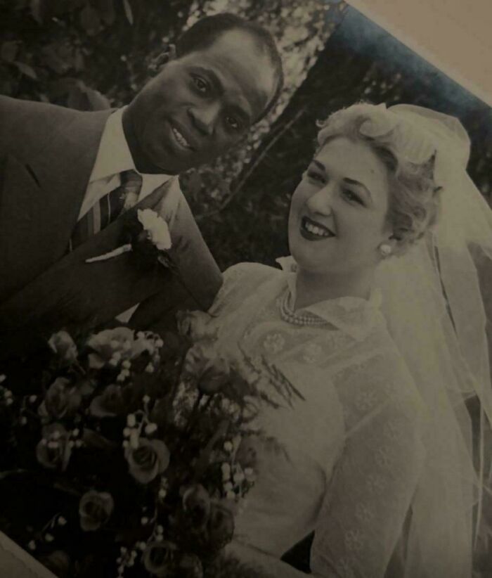 Vintage wedding photo of an interracial couple smiling, capturing a moment from decades ago in a black and white image.