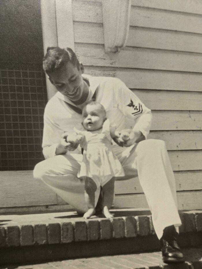 Vintage photo of a sailor holding a baby, capturing a heartfelt moment from decades ago with timeless emotion.