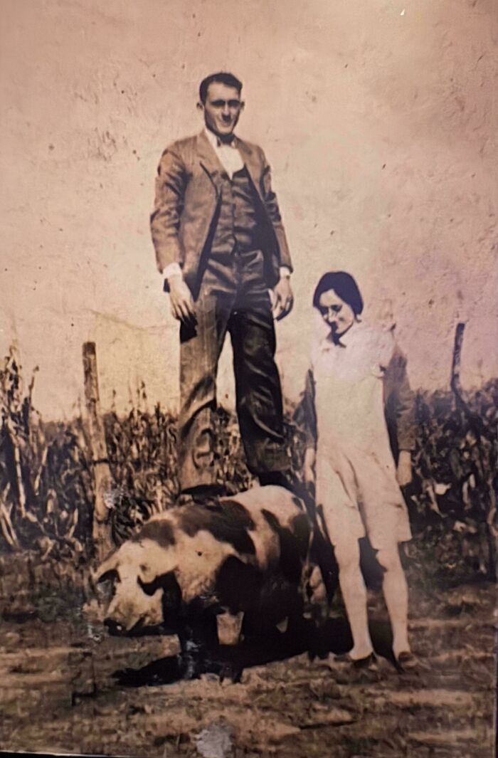 Vintage photo of a man standing on a pig and a woman nearby, capturing moments from decades ago with historic significance.
