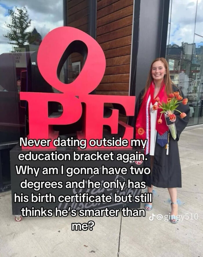 Woman in graduation robe holding flowers next to large red hope sign, sharing a humorous education moment.