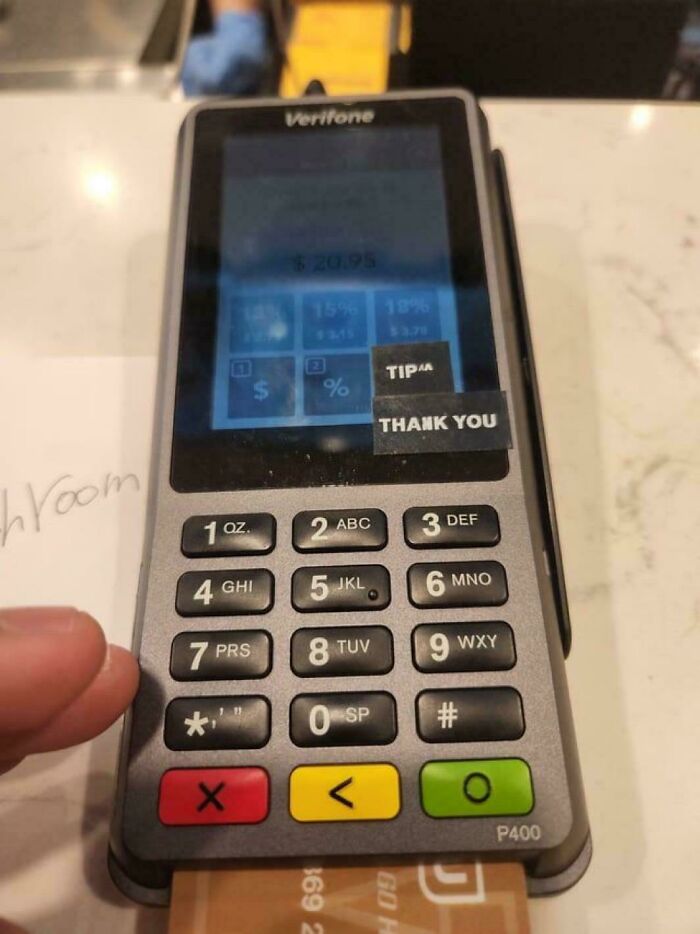 Payment terminal with a screen partially covered by tip and thank you stickers, highlighting favorite internet moments.