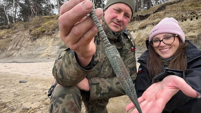 Two people outdoors showing a fascinating artefact that survived to this day, highlighting history and humanity.