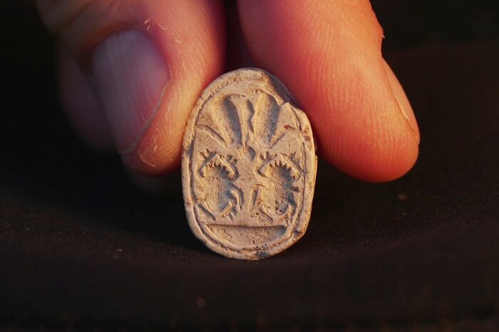 Ancient artefact held between fingers showing detailed carvings, representing fascinating artefacts that survived to this day.