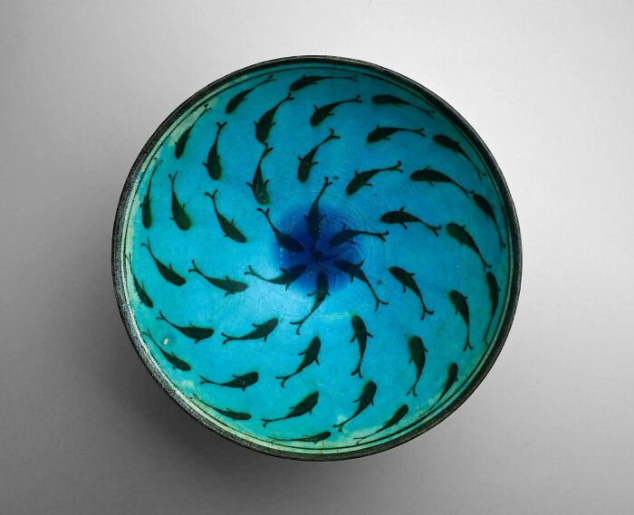 Blue ceramic bowl with black fish patterns, an ancient artefact representing historical world and humanity perspective.