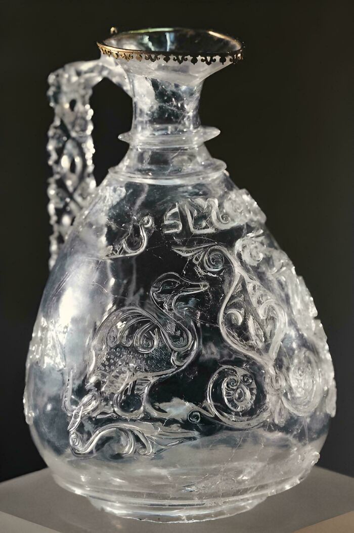 Ancient glass artefact with intricate animal engravings and ornate handle, showcasing craftsmanship that survived through history.