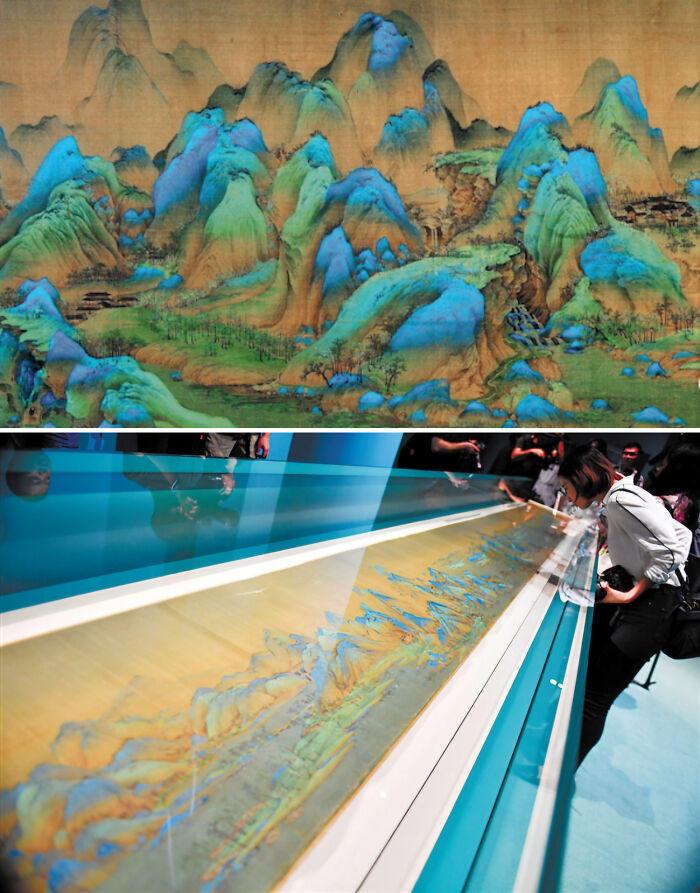 Ancient colorful landscape scroll displayed in a museum with visitors observing artefact showcasing world history.