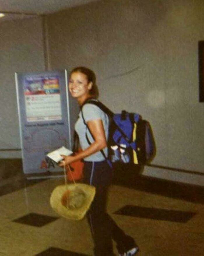 Young traveler smiling with backpack and hat indoors, showcasing strange Earth experiences during adventurous journey.