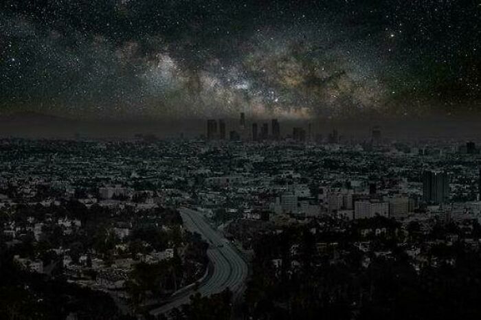 City skyline at night with a vivid Milky Way galaxy overhead, showcasing strange Earth phenomena in the world.