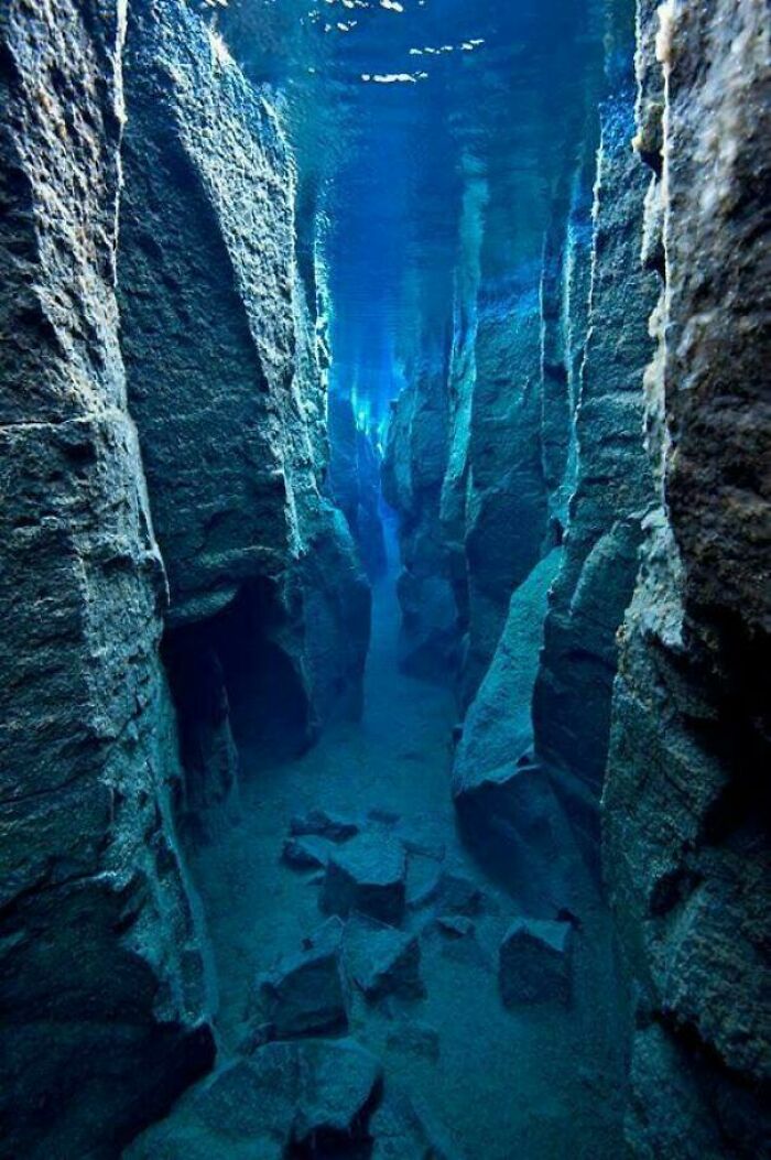 Underwater rock formations in a deep ocean canyon showing strange earth features and surreal natural beauty.
