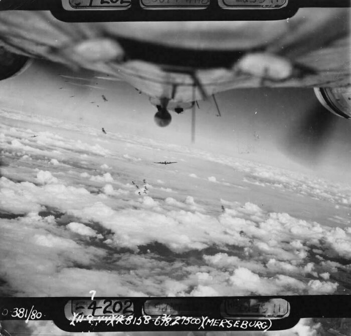 Black and white historical photo of World War II bomber planes flying above the clouds during a mission.