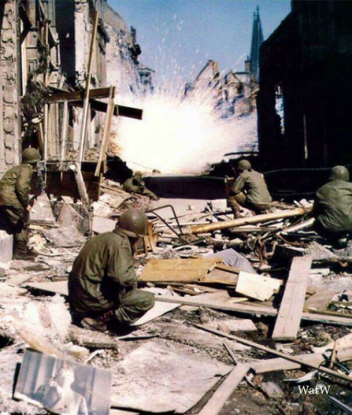 Soldiers taking cover amidst rubble as an explosion erupts during a historical battle, representing a vastly different world.