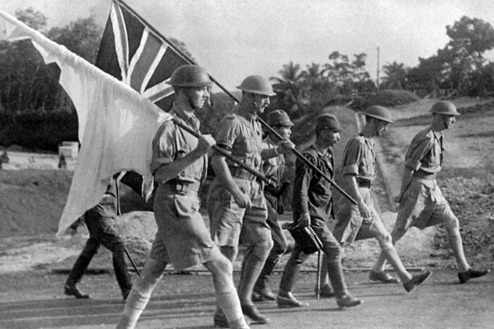 Black and white historical photo of soldiers marching with flags, representing a vastly different world from today.