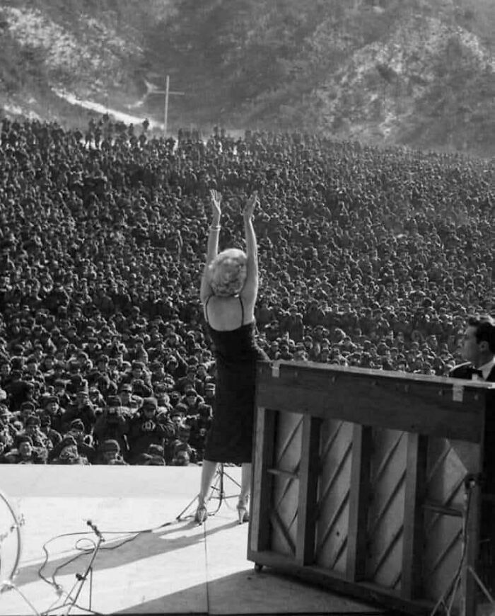 Vintage photo of a female performer entertaining a massive crowd, showcasing historical moments from a vastly different world.