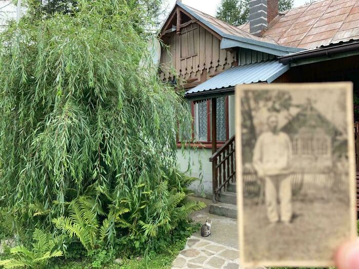 Old black and white photo held in front of a traditional house and garden, illustrating historical photos representing a different world.