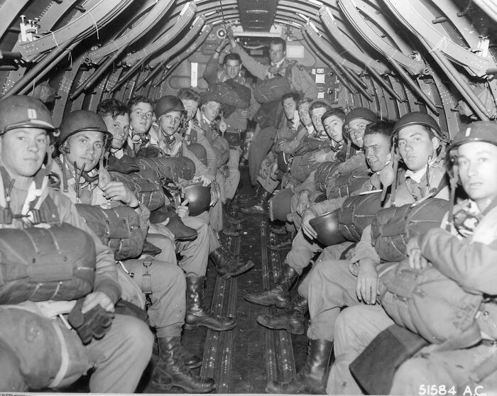 Group of soldiers seated inside a military aircraft, representing historical photos from a vastly different world.